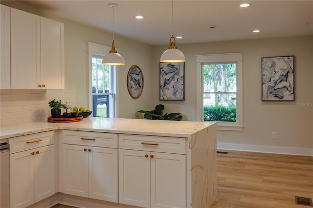 kitchen with white cabinetry, visible vents, a peninsula, and light stone countertops