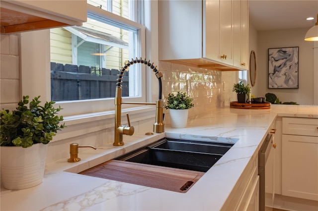 room details with light stone counters, white cabinets, a sink, and decorative backsplash