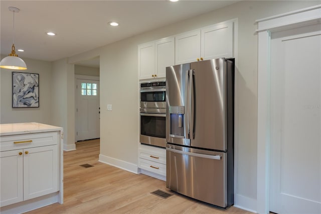 kitchen featuring stainless steel appliances, white cabinetry, visible vents, and decorative light fixtures