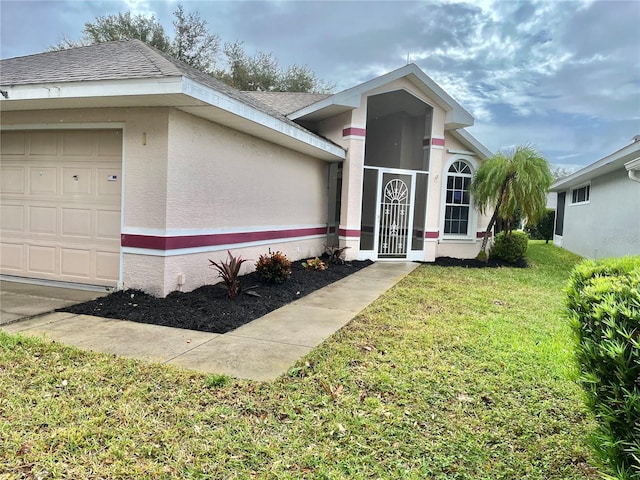 entrance to property featuring roof with shingles, a lawn, an attached garage, and stucco siding