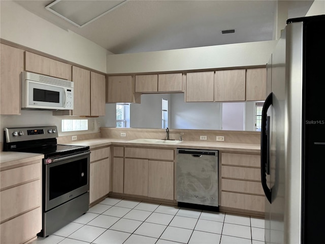 kitchen with stainless steel appliances, light countertops, a sink, and light brown cabinetry