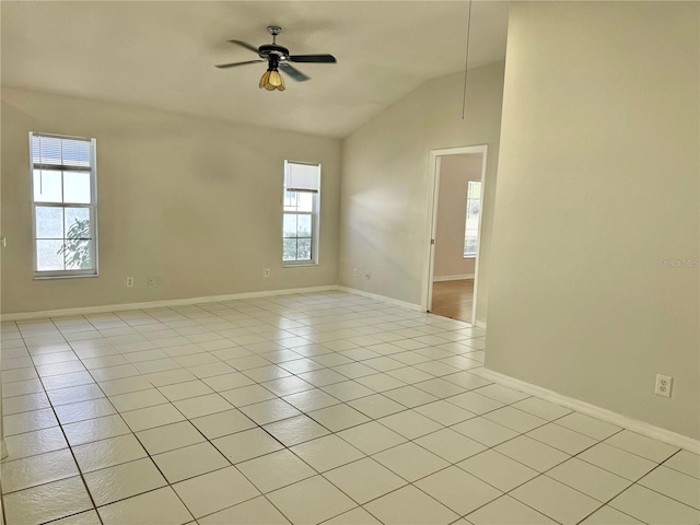 unfurnished room with lofted ceiling, light tile patterned flooring, a ceiling fan, and baseboards