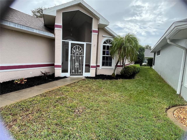 entrance to property with a yard and stucco siding