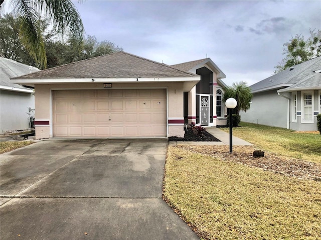 single story home featuring an attached garage, driveway, a front lawn, and stucco siding