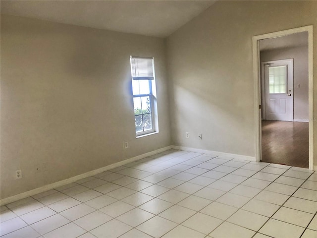 empty room with baseboards and light tile patterned floors