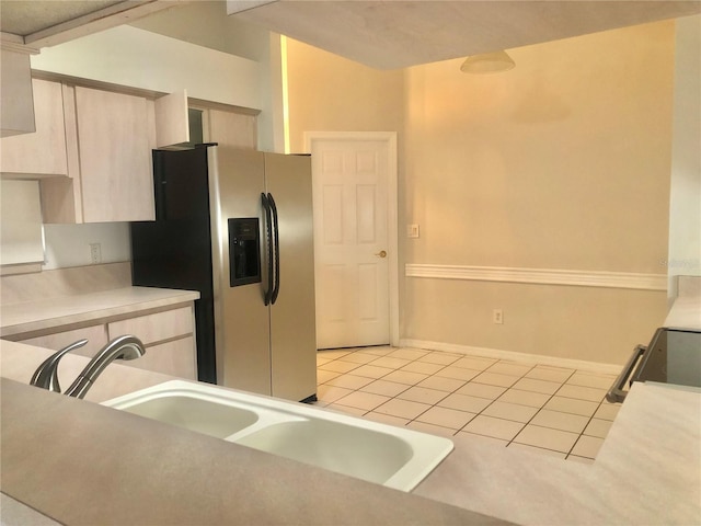 kitchen featuring light countertops, light tile patterned flooring, a sink, and stainless steel fridge with ice dispenser