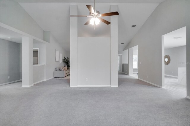 unfurnished living room with ceiling fan, high vaulted ceiling, and light carpet