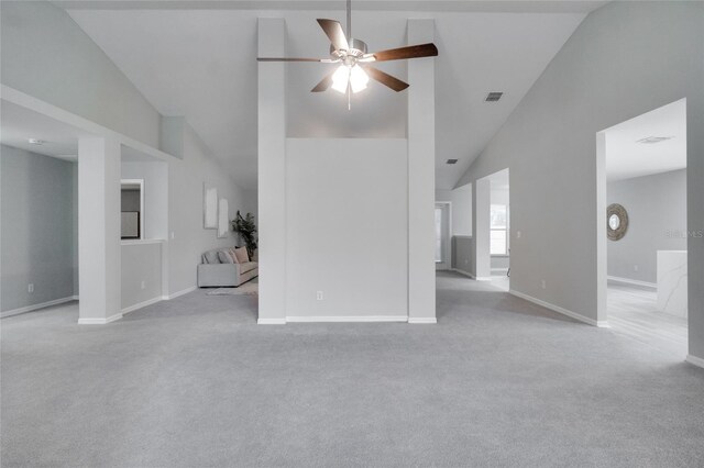 unfurnished living room with high vaulted ceiling, ceiling fan, and light colored carpet