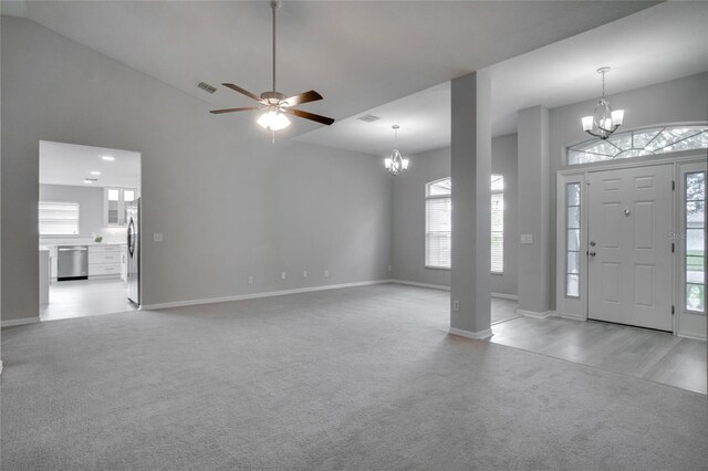 carpeted entryway with ceiling fan with notable chandelier and high vaulted ceiling