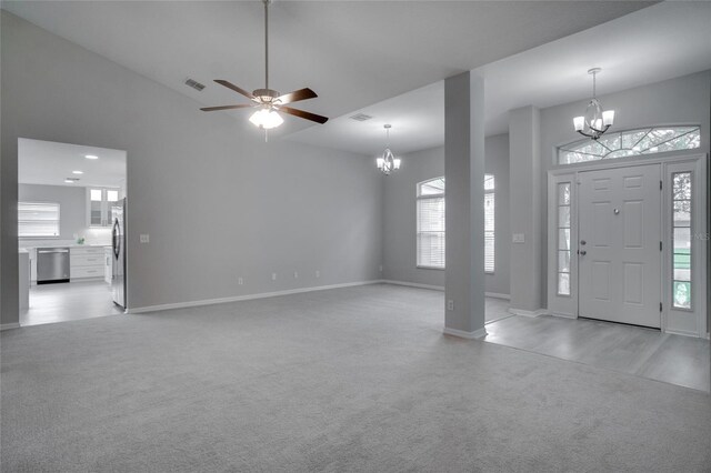 foyer entrance featuring ceiling fan with notable chandelier, a wealth of natural light, and light carpet