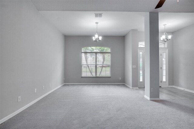 empty room featuring carpet flooring and ceiling fan with notable chandelier