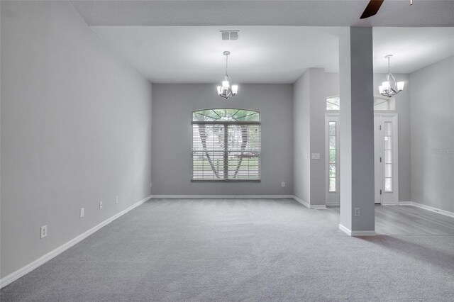 carpeted spare room featuring ceiling fan with notable chandelier and a wealth of natural light