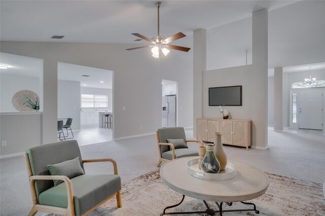 living room with ceiling fan with notable chandelier, high vaulted ceiling, and light carpet