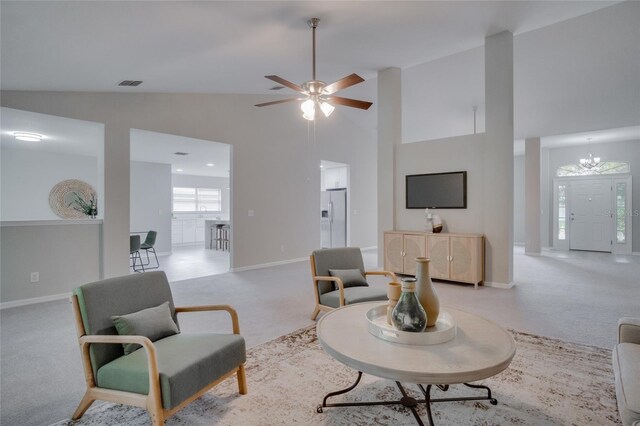 living room featuring high vaulted ceiling, ceiling fan with notable chandelier, and light colored carpet