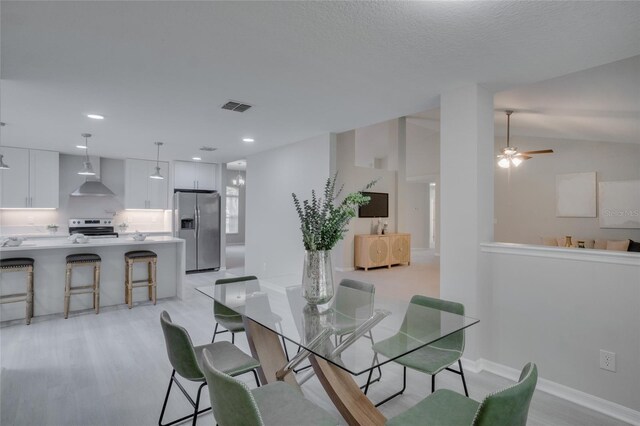 dining area featuring ceiling fan, light hardwood / wood-style floors, and vaulted ceiling