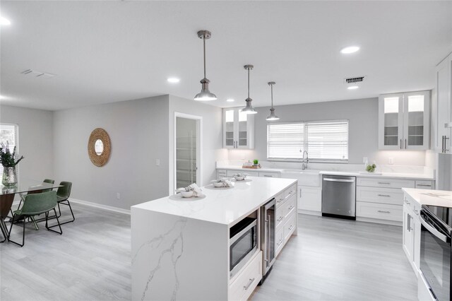 kitchen with white cabinetry, appliances with stainless steel finishes, and light hardwood / wood-style flooring