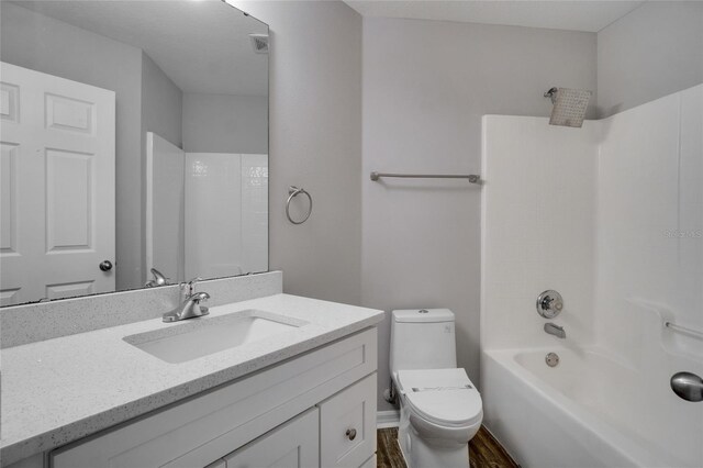 full bathroom featuring bathing tub / shower combination, toilet, hardwood / wood-style floors, and vanity