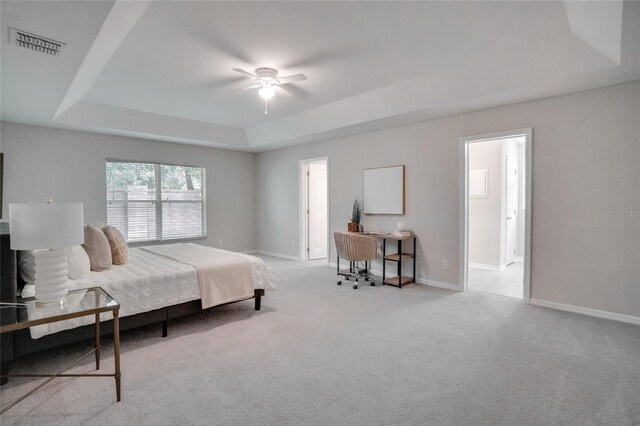 bedroom featuring ceiling fan, light colored carpet, and a tray ceiling