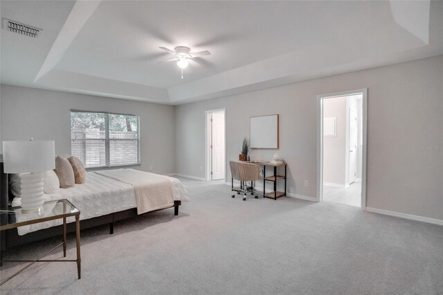 bedroom featuring light colored carpet, a tray ceiling, and ceiling fan