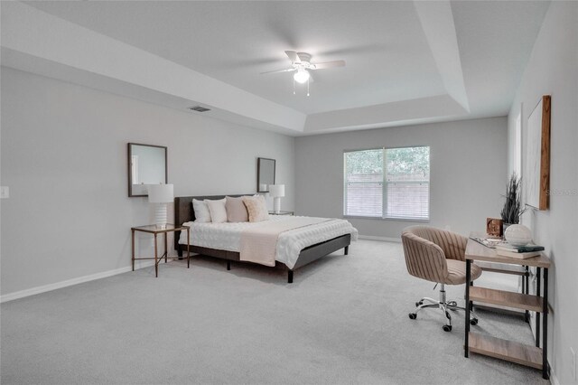 carpeted bedroom featuring ceiling fan and a raised ceiling