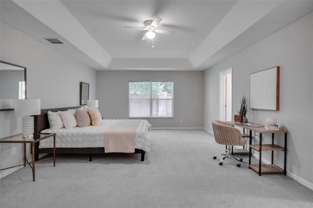 bedroom with ceiling fan, a raised ceiling, and light carpet