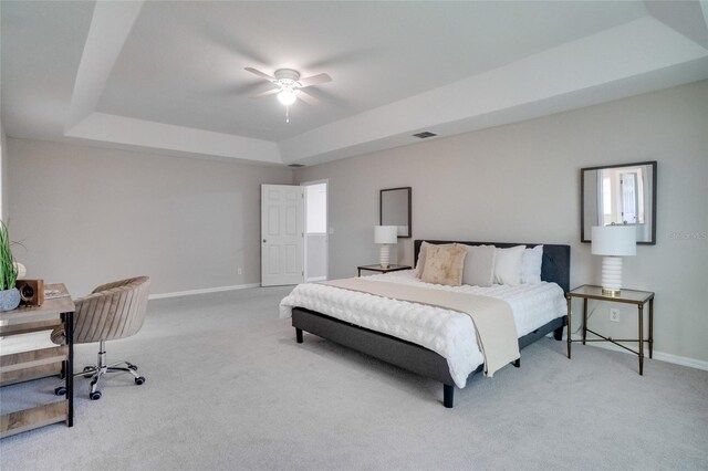 carpeted bedroom with ceiling fan and a raised ceiling