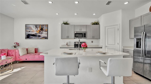 kitchen featuring appliances with stainless steel finishes, light countertops, a sink, and an island with sink