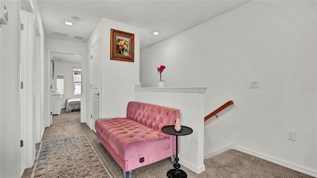 hallway featuring carpet, visible vents, baseboards, and an upstairs landing