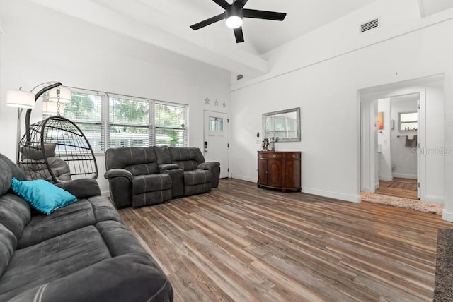 living room with ceiling fan, hardwood / wood-style flooring, and a towering ceiling