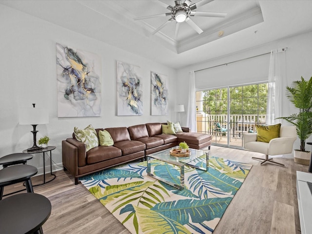 living room with a tray ceiling, ceiling fan, crown molding, and wood-type flooring