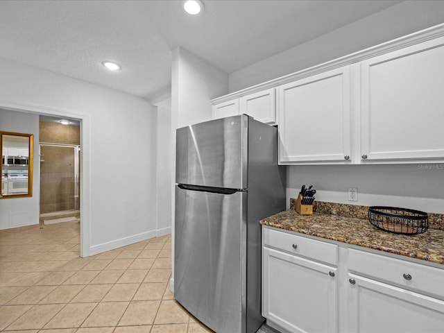 kitchen featuring light tile patterned flooring, recessed lighting, stainless steel appliances, white cabinets, and dark stone countertops