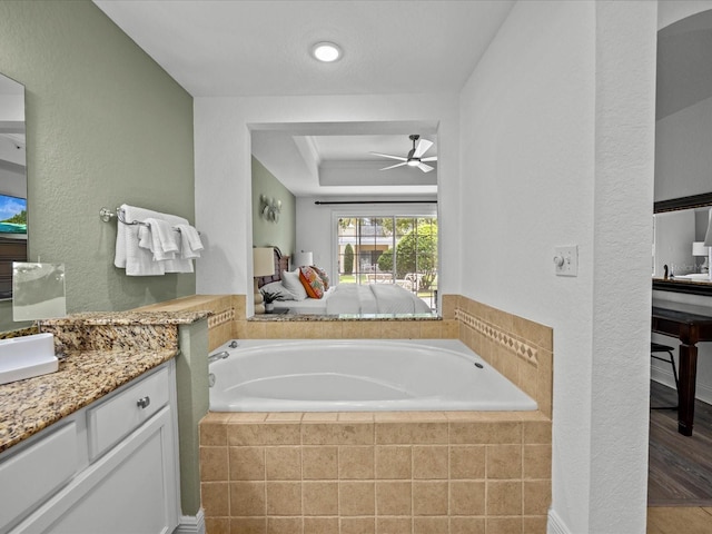 bathroom with wood-type flooring, vanity, tiled bath, and ceiling fan