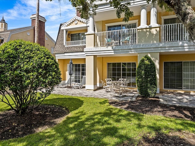 back of house with a lawn, a balcony, and a patio