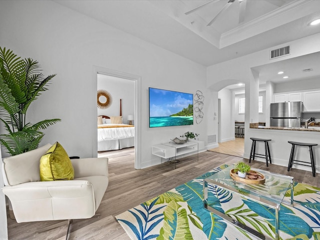 living room featuring light wood-type flooring, ceiling fan, and sink