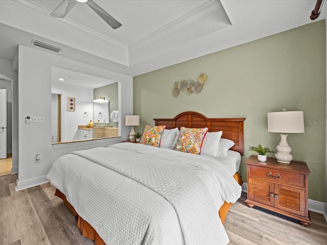 bedroom with ceiling fan, crown molding, a tray ceiling, and light hardwood / wood-style flooring