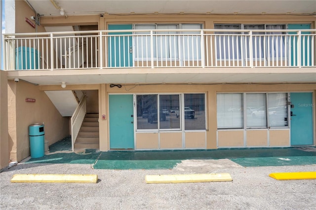 entrance to property featuring uncovered parking and stucco siding