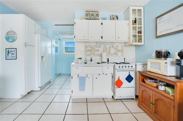 kitchen with white appliances, white cabinetry, and light tile patterned floors