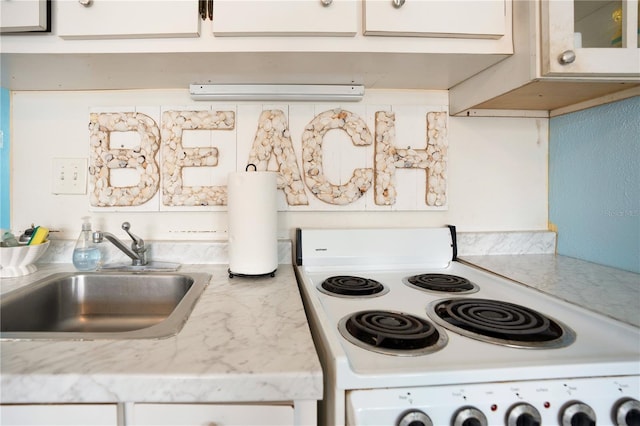 kitchen with sink, white cabinetry, and stove