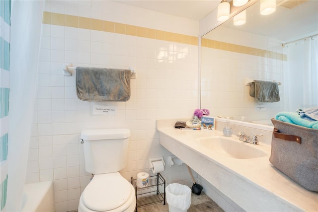 bathroom with toilet, a sink, tile walls, and shower / tub combo with curtain