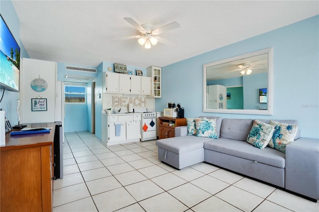 living room with light tile patterned flooring, ceiling fan, and a textured ceiling