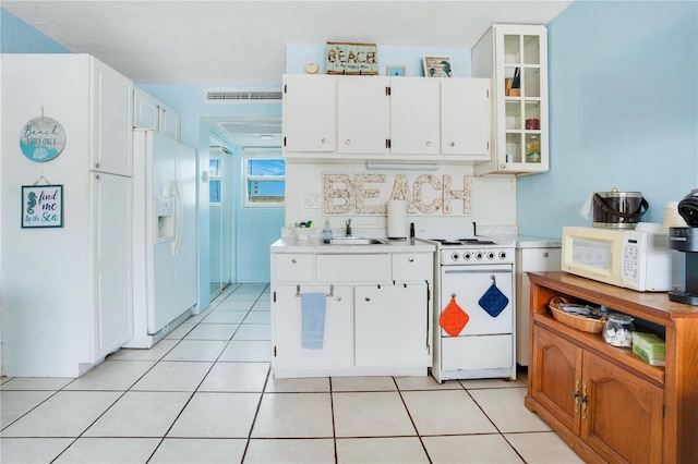 kitchen with white appliances, white cabinetry, glass insert cabinets, and light countertops