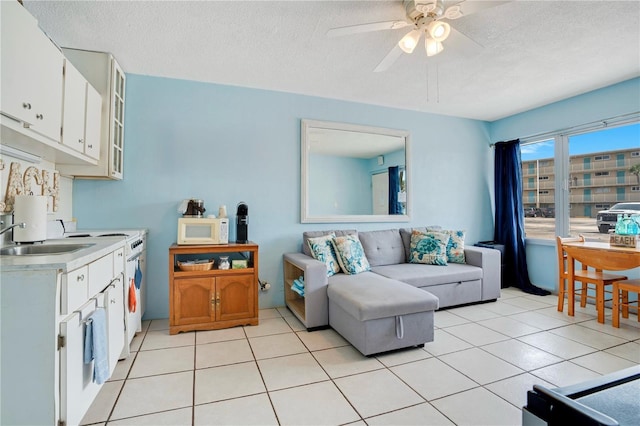 living room with ceiling fan, a textured ceiling, and light tile patterned flooring