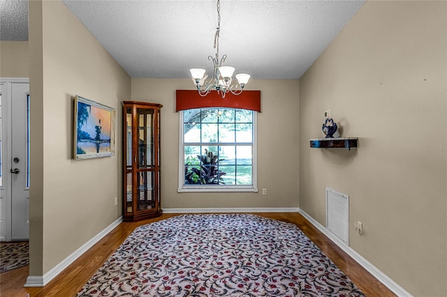 interior space with a textured ceiling, a chandelier, and wood-type flooring