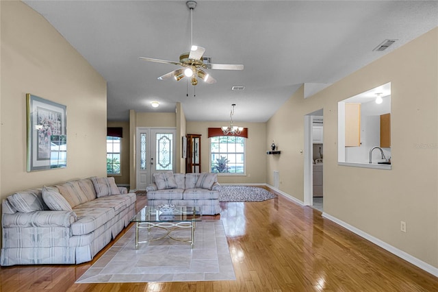 living room with sink, vaulted ceiling, light hardwood / wood-style flooring, and ceiling fan with notable chandelier