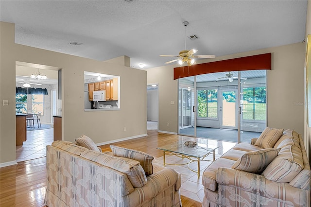 living room featuring a textured ceiling, ceiling fan, and light hardwood / wood-style floors