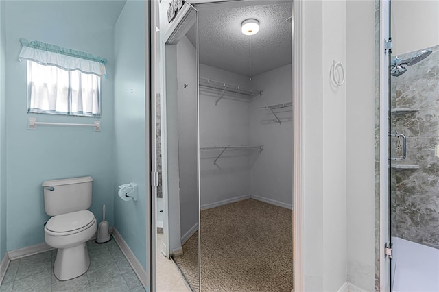 bathroom with tile patterned flooring, an enclosed shower, toilet, and a textured ceiling