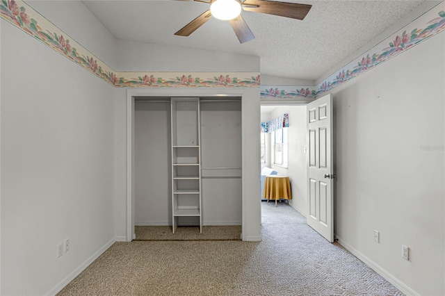 unfurnished bedroom with a textured ceiling, lofted ceiling, a closet, ceiling fan, and light carpet