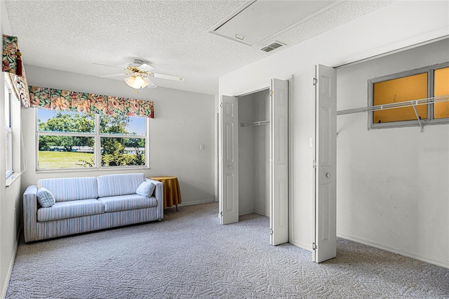 interior space featuring ceiling fan, a textured ceiling, and light colored carpet