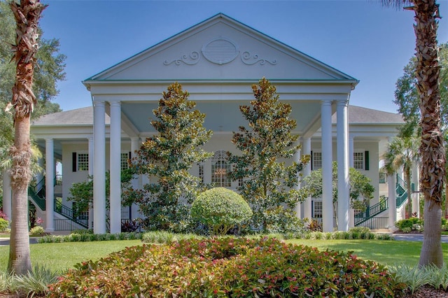 neoclassical home featuring a front lawn