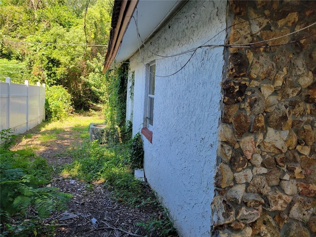 view of side of property featuring stucco siding and fence